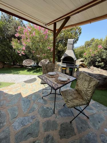 un patio avec une table, des chaises et une cheminée dans l'établissement Studio de charme à 300 m de la Plage de Santa Giulia, à Porto-Vecchio