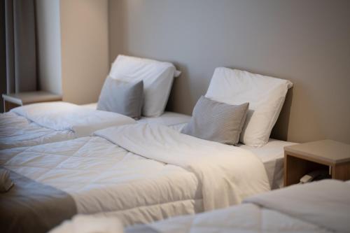two beds in a room with white sheets and pillows at Hotel Kaikis in Kalabaka