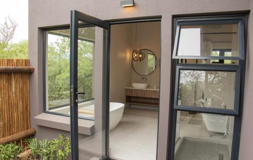 baño con bañera y puerta de cristal en Villa Tau, en Hoedspruit