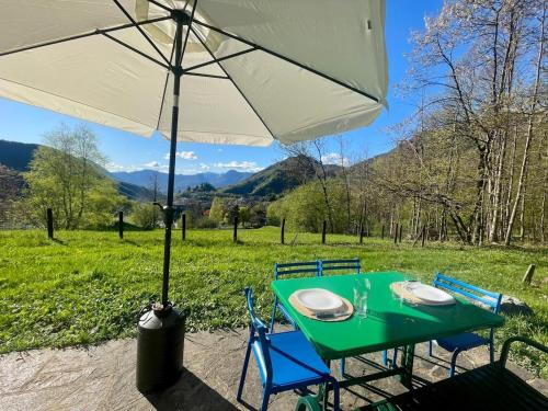 a green table and chairs with an umbrella at Il Casello Bigallo in Esino Lario
