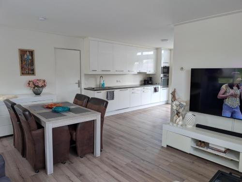 a kitchen and dining room with a table and a tv at De Merel in Leeuwarden