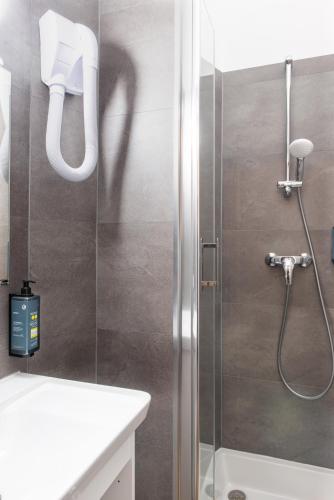 une salle de bain avec une douche avec une porte vitrée dans l'établissement Hôtel Coypel by Magna Arbor, à Paris