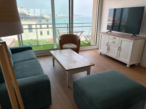 un salon avec une télévision, un canapé et une table dans l'établissement Vue sur Mer Appartement les Sables d'Olonne - 6 personnes, à Les Sables-dʼOlonne