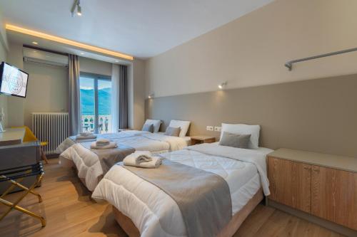 a hotel room with three beds and a flat screen tv at Hotel Kaikis in Kalabaka