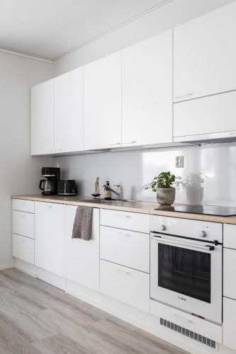 a white kitchen with white cabinets and a sink at Villa Kesäranta in Oulu