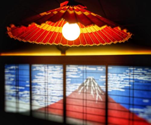 a red and yellow umbrella hanging from a ceiling at Japanese Style Hotel WAKUWAKU-BASE Nakasendo Yabuharajuku