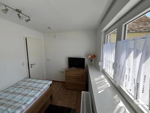 a bedroom with a bed and a tv and a window at Haus Budinger in Alf