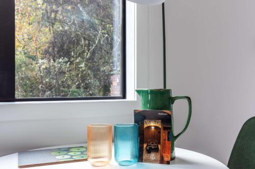 a green vase sitting on a table with two cups at The Grove Turangi in Turangi
