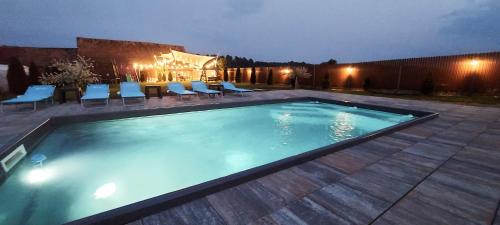 a swimming pool at night with chairs and a table at Casa Simion in Sibiu