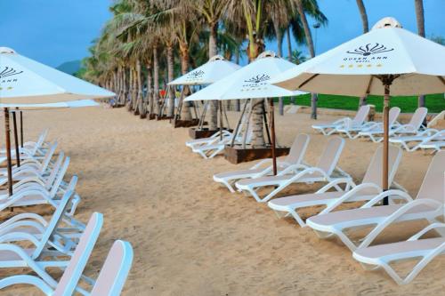 a row of chairs and umbrellas on a beach at Queen Ann Nha Trang Hotel in Nha Trang