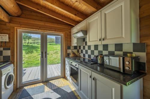 a kitchen with a stove top oven next to a door at Finest Retreats - Cragdhu Log Cabin in Glenshee