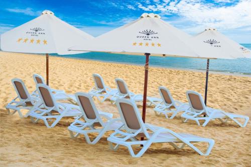 a group of chairs and umbrellas on a beach at Queen Ann Nha Trang Hotel in Nha Trang