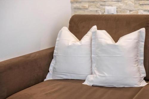 two white pillows sitting on a brown couch at Morgensonne in Maranza