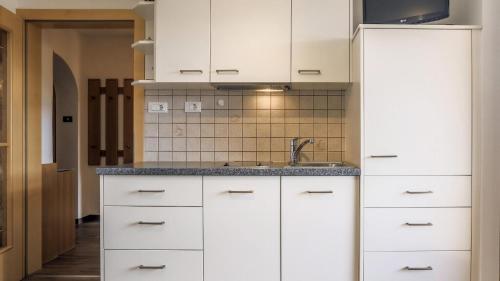 a kitchen with white cabinets and a sink at Morgensonne in Maranza