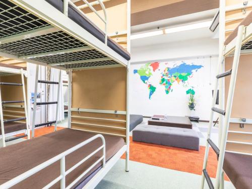 a student dorm room with bunk beds and a map of the world at Omotenashi Hostel Miyajima in Hatsukaichi