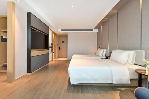 a hotel room with two beds and a flat screen tv at Atour Hotel Shenyang North Station in Shenyang