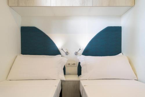 two beds in a small room with two lamps at Camping Fontanelle in Moniga