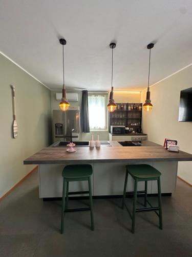 a kitchen with a large island with two green bar stools at Villa Giulia in Sulzano