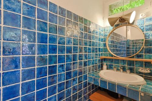 La salle de bains est pourvue de carrelage bleu, d'un lavabo et d'un miroir. dans l'établissement Villa les Vignes Basses - Saint Tropez, à Saint-Tropez