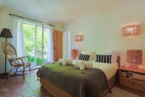 une chambre avec un lit, une chaise et une fenêtre dans l'établissement Villa les Vignes Basses - Saint Tropez, à Saint-Tropez