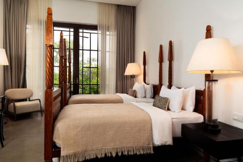 two beds in a hotel room with two lamps at Lily Pod in Panadura