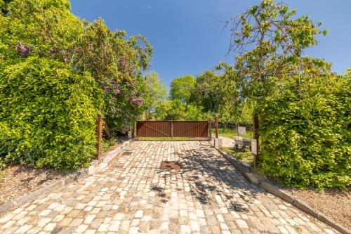 a brick driveway with trees and a fence at GITE Cocotte La Roulotte in Fauvillers