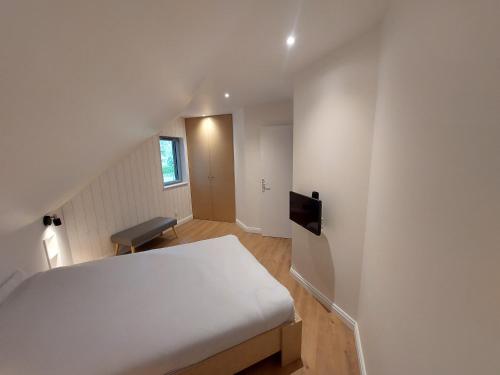 une chambre avec un lit blanc et un escalier dans l'établissement Le Cottage des Forges, à Longueil