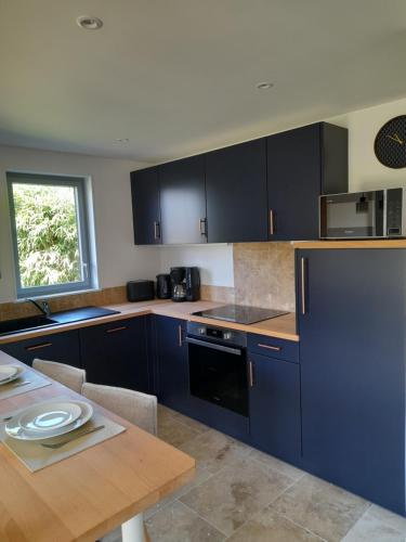 une cuisine avec des placards bleus et une table en bois dans l'établissement Le Cottage des Forges, à Longueil