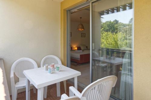 une table blanche et des chaises dans une pièce avec une fenêtre dans l'établissement Le Gîte de l’Estuaire - Proche Plage, à Saint-Georges-de-Didonne