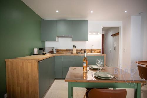 une cuisine avec des armoires vertes et une table avec une bouteille dessus dans l'établissement Lovely renovated studio in the heart of Cannes, à Cannes