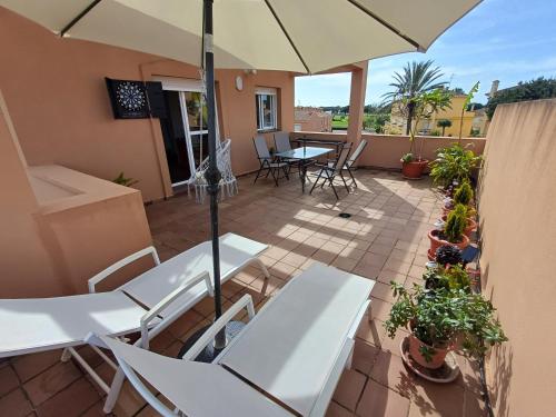 a patio with white tables and chairs and an umbrella at Ático "El Palomar" Rooftop in Novo Sancti Petri