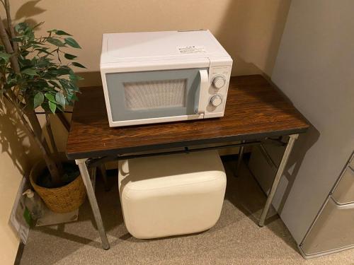 un microondas sentado en una mesa junto a una planta en e-hostel 心斎橋, en Osaka