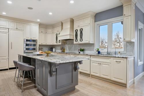 a kitchen with white cabinets and a large island at The Royal Ravine Luxury Retreat in Calgary