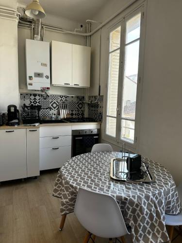 une cuisine avec une table et des chaises et une cuisine avec des armoires blanches dans l'établissement Nouveau Palais, à Toulon