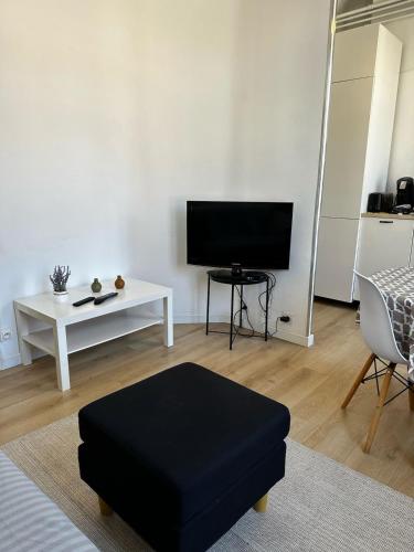 un salon avec un pouf noir et une télévision dans l'établissement Nouveau Palais, à Toulon