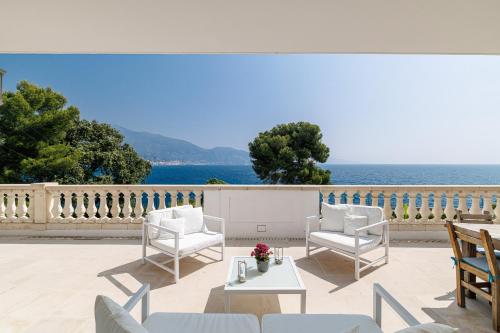 a patio with white chairs and a table with a view of the ocean at Villa Ocean Breeze in Roquebrune-Cap-Martin
