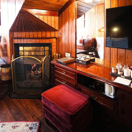 a living room with a fireplace and a desk with a table at Mayfair Darjeeling in Darjeeling