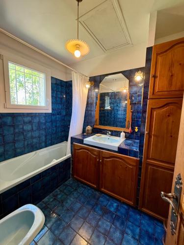 La salle de bains est pourvue de carrelage bleu, d'une baignoire et d'un lavabo. dans l'établissement Vacances en famille dans le Sud, à Rousson