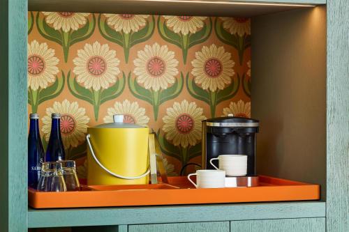 a shelf with bottles and cups and a wallpaper with flowers at the Curtis Denver - A DoubleTree by Hilton Hotel in Denver