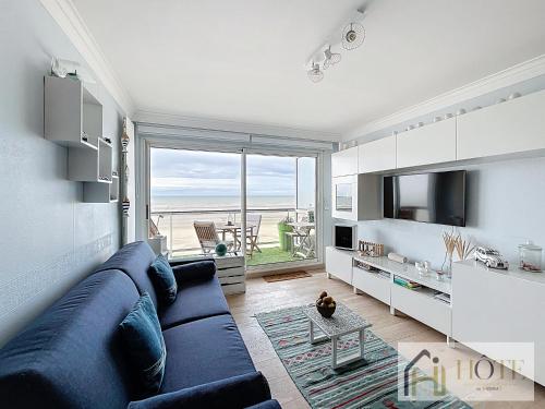 - un salon avec un canapé bleu et une vue sur l'océan dans l'établissement Doux Rivage- Studio Vue Mer, à Bray-Dunes