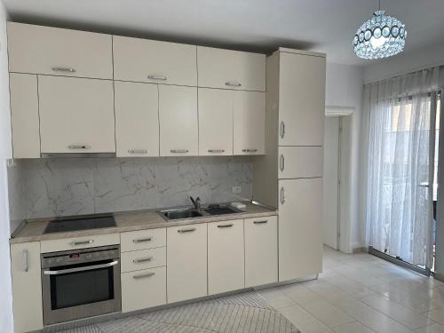 a white kitchen with white cabinets and a chandelier at Sole Inn Apartment in Durrës