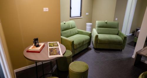 a waiting room with two green chairs and a table at Opera Hotel in Gravina in Puglia
