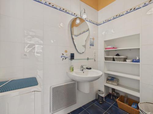 une salle de bain blanche avec un lavabo et un miroir dans l'établissement Maison bretonne pour 4 adultes et 3 enfants, à Saint-Gildas-de-Rhuys