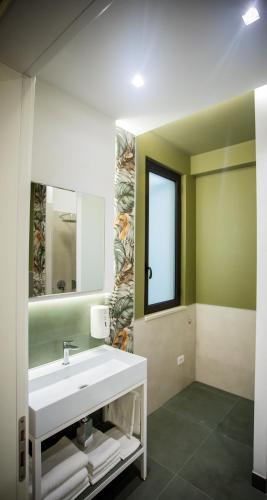 a bathroom with a white sink and a mirror at Opera Hotel in Gravina in Puglia