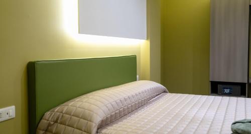 a bedroom with a bed with a green headboard at Opera Hotel in Gravina in Puglia