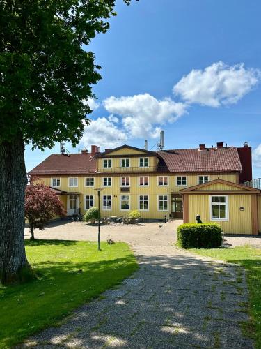 a large yellow building with a tree in front of it at Ljungskile Hotell & Konferens in Ljungskile