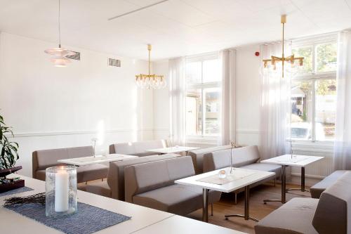 a restaurant with tables and chairs and windows at Ljungskile Hotell & Konferens in Ljungskile