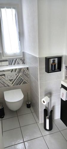une salle de bain blanche avec toilettes et fenêtre dans l'établissement Gîte Portsallais, à Ploudalmézeau