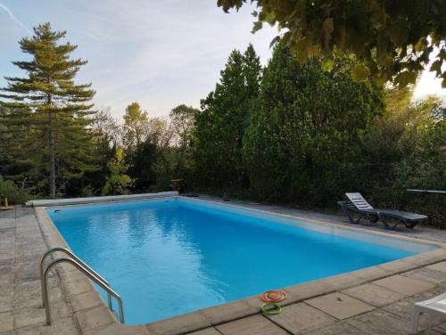 une grande piscine bleue avec un banc et des arbres dans l'établissement Vacances en famille dans le Sud, à Rousson
