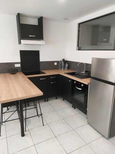 une cuisine avec un réfrigérateur en acier inoxydable et une table dans l'établissement Navarrenx centre historique - appartement T2, à Navarrenx